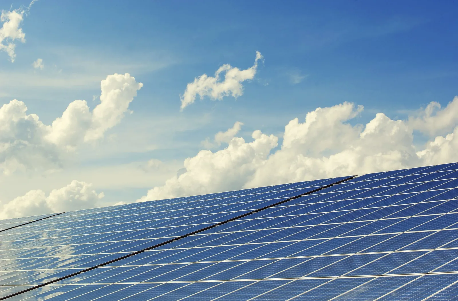 Solar panels beneath a wide, cloud-filled sky